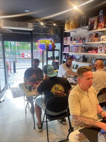 Spelers aan de speeltafels in de winkel van Hero Zone